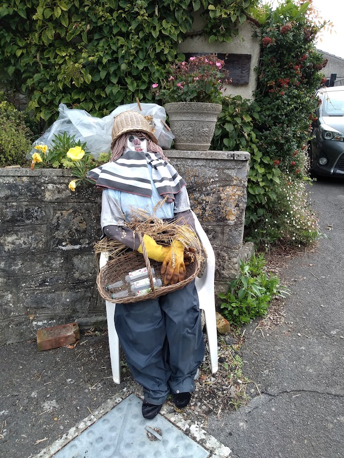 Scarecrow with a basket of empty drink bottles